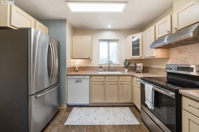 kitchen featuring appliances with stainless steel finishes, under cabinet range hood, a sink, glass insert cabinets, and light countertops