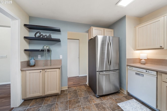 kitchen featuring white dishwasher, freestanding refrigerator, light brown cabinets, baseboards, and light countertops