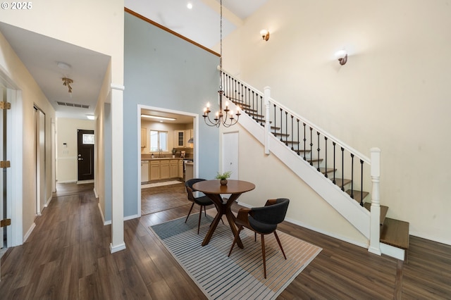 dining room with dark wood-style flooring, stairway, a high ceiling, and baseboards