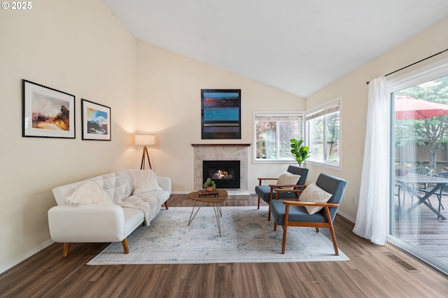 living area featuring wood finished floors, baseboards, lofted ceiling, and a fireplace