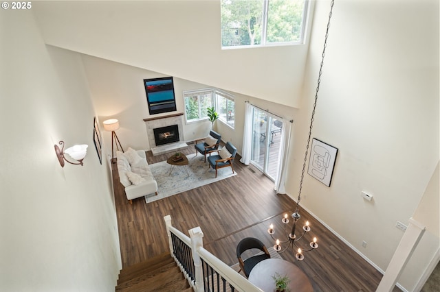 living room with a glass covered fireplace, baseboards, a high ceiling, and wood finished floors