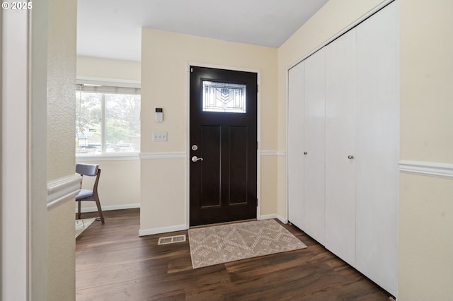 foyer entrance with dark wood-type flooring, plenty of natural light, and baseboards