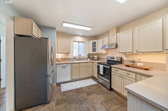 kitchen featuring appliances with stainless steel finishes, under cabinet range hood, a sink, light countertops, and recessed lighting