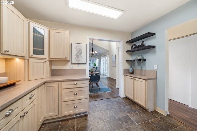 kitchen with light countertops, baseboards, a chandelier, open shelves, and cream cabinetry