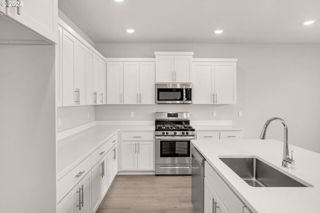 kitchen featuring stainless steel appliances, sink, white cabinets, and light hardwood / wood-style floors