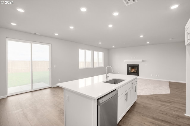 kitchen with recessed lighting, a sink, open floor plan, dishwasher, and a glass covered fireplace