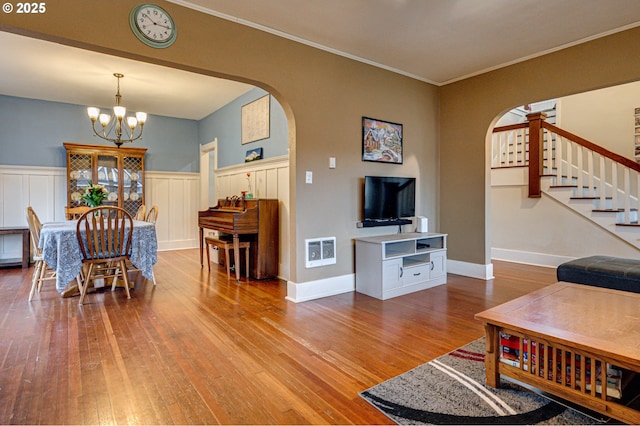 living room featuring hardwood / wood-style flooring, stairs, arched walkways, and a chandelier