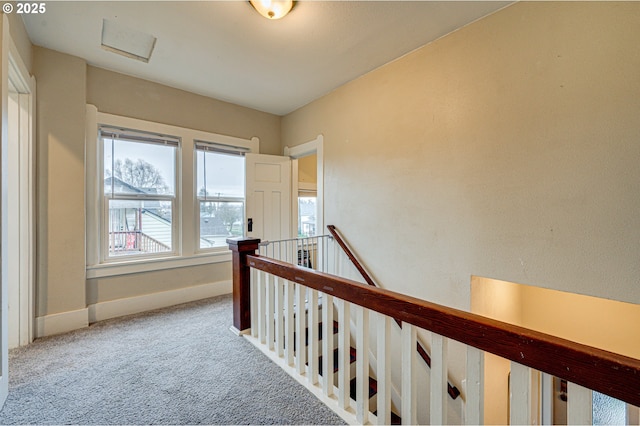 hallway with attic access, carpet flooring, an upstairs landing, and baseboards