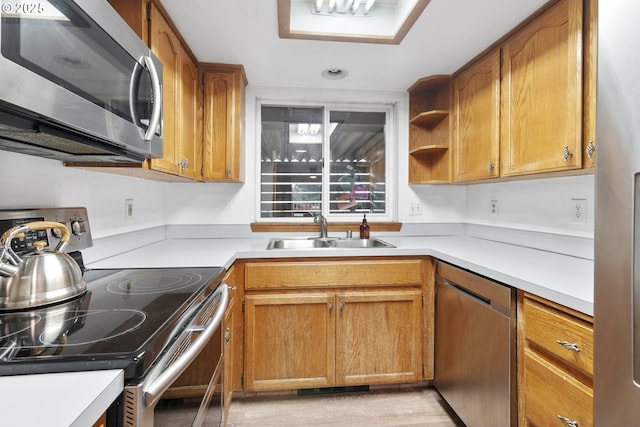 kitchen featuring stainless steel appliances, brown cabinetry, a sink, and light countertops