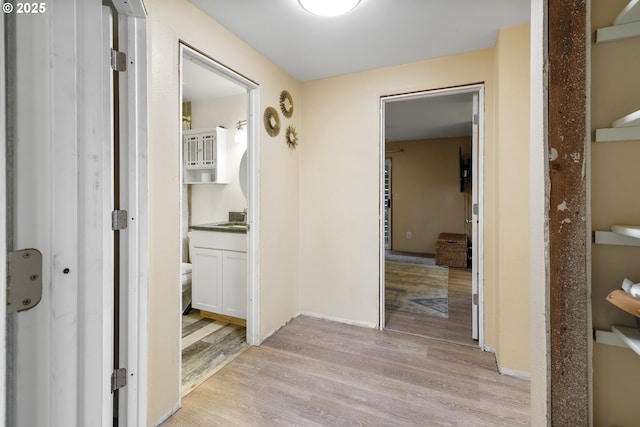 hall with light wood-style flooring and baseboards