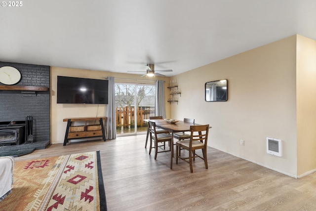 dining room featuring a wood stove, heating unit, a ceiling fan, and wood finished floors