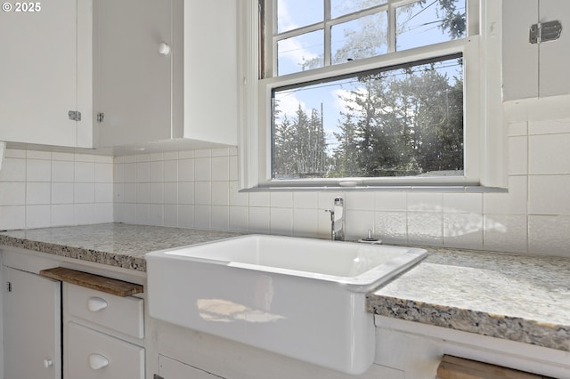 kitchen with a healthy amount of sunlight, decorative backsplash, and white cabinets