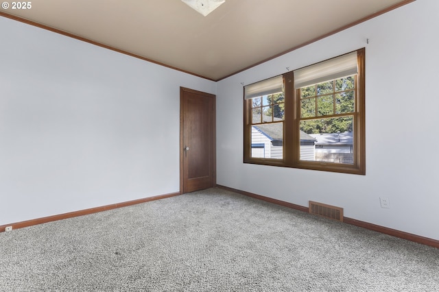 empty room featuring carpet, crown molding, visible vents, and baseboards