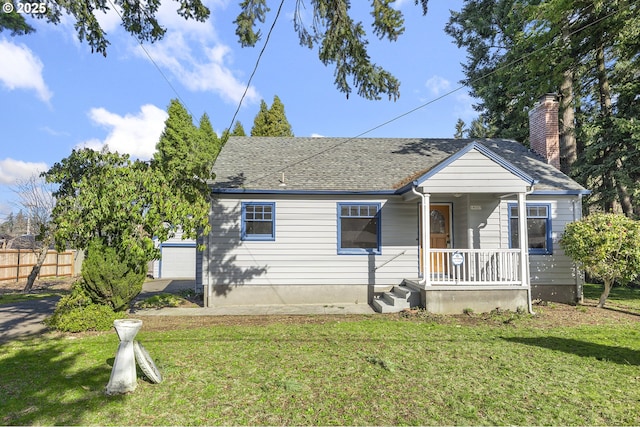 bungalow-style house with covered porch, fence, a chimney, and a front lawn