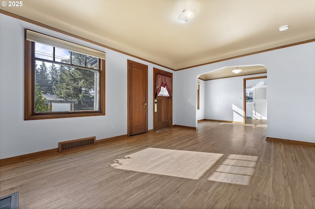 entryway featuring arched walkways, ornamental molding, wood finished floors, and visible vents