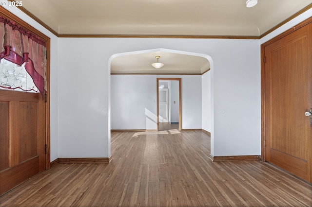 entryway with baseboards, crown molding, arched walkways, and wood finished floors