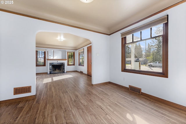 unfurnished living room featuring visible vents, arched walkways, and wood finished floors