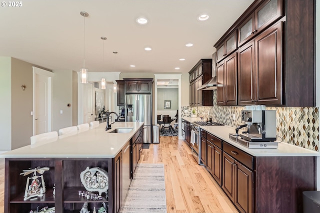 10183 NW Crossing Dr, Portland, OR 97229 - kitchen featuring appliances with stainless steel finishes, dark brown cabinetry, a sink, light wood-type flooring, and a center island with sink