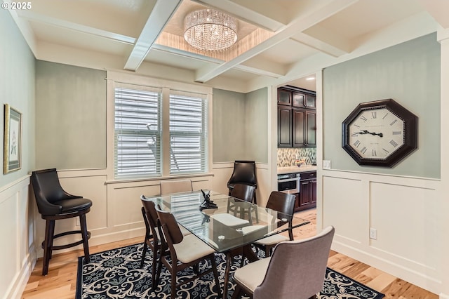 10183 NW Crossing Dr, Portland, OR 97229 - dining space with coffered ceiling, light wood finished floors, a chandelier, a decorative wall, and beamed ceiling