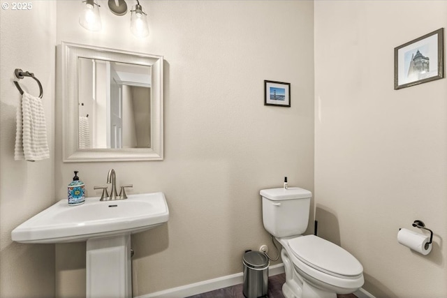 bathroom featuring a sink, toilet, and baseboards