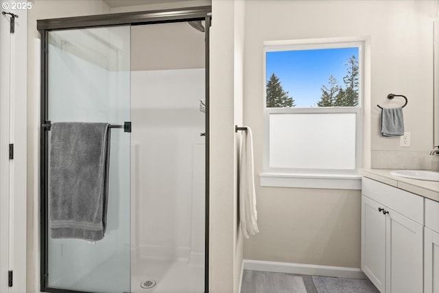 full bath featuring a stall shower, baseboards, and vanity