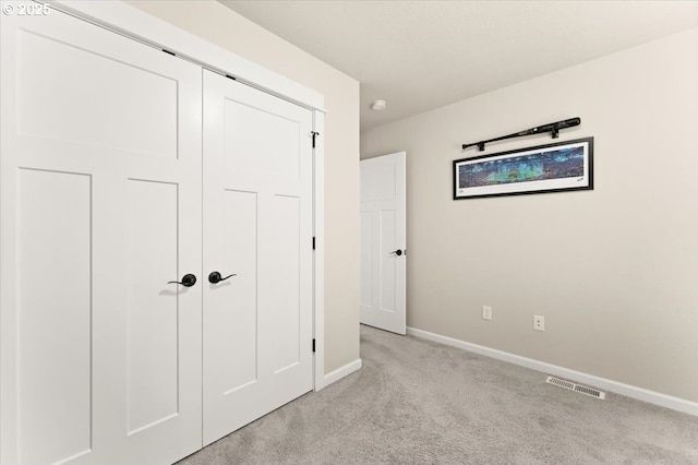 unfurnished bedroom with light colored carpet, a closet, visible vents, and baseboards