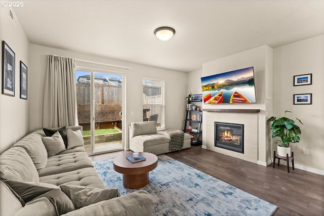 living area with a tile fireplace, wood finished floors, and baseboards