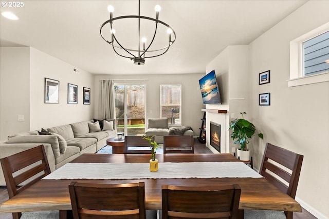 dining area featuring a glass covered fireplace and an inviting chandelier