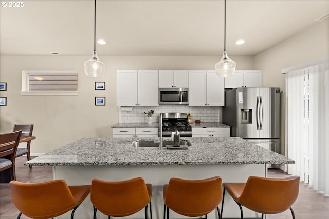 kitchen with white cabinets, tasteful backsplash, a breakfast bar area, and stainless steel appliances