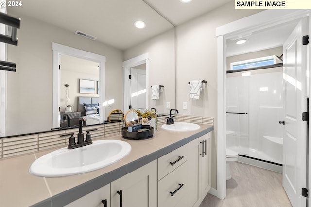 bathroom with a shower with door, vanity, and toilet