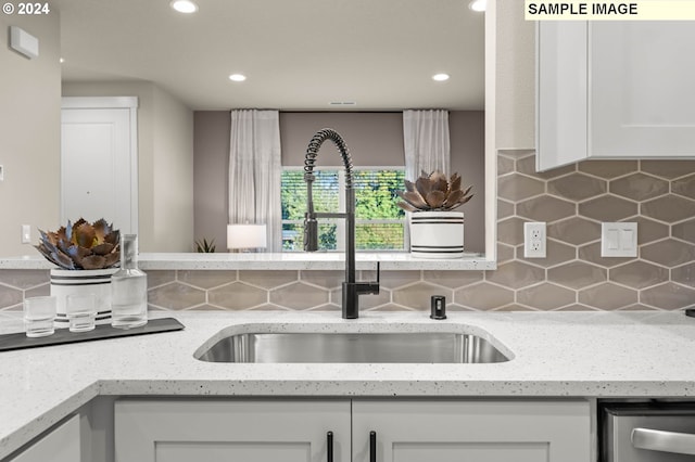 kitchen featuring light stone countertops, white cabinetry, tasteful backsplash, and sink