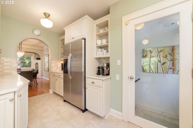 4052 NE 22nd Ave, Portland, OR 97212 - kitchen featuring stainless steel refrigerator with ice dispenser, arched walkways, backsplash, light countertops, and white cabinetry