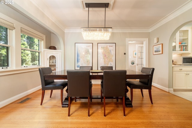 4052 NE 22nd Ave, Portland, OR 97212 - dining space featuring a chandelier, light wood finished floors, arched walkways, and ornamental molding