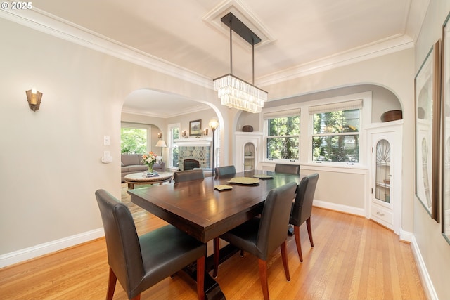 4052 NE 22nd Ave, Portland, OR 97212 - dining area with a fireplace, arched walkways, light wood-type flooring, and crown molding