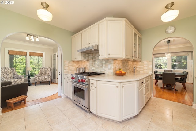 4052 NE 22nd Ave, Portland, OR 97212 - kitchen featuring premium range, arched walkways, under cabinet range hood, light countertops, and ornamental molding