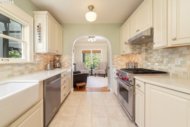 4052 NE 22nd Ave, Portland, OR 97212 - kitchen featuring appliances with stainless steel finishes, under cabinet range hood, arched walkways, light countertops, and light tile patterned flooring