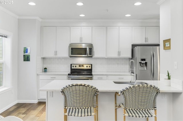 kitchen featuring a kitchen breakfast bar, ornamental molding, appliances with stainless steel finishes, and a sink