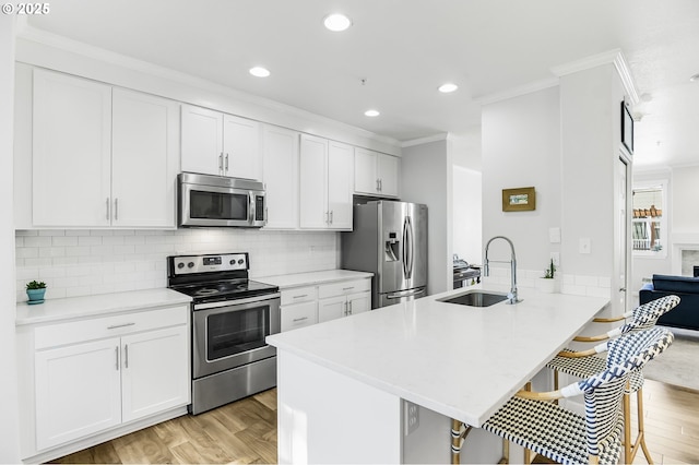 kitchen with a sink, a kitchen bar, appliances with stainless steel finishes, and ornamental molding