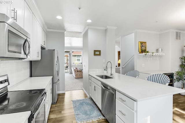 kitchen with tasteful backsplash, light wood finished floors, crown molding, appliances with stainless steel finishes, and a sink