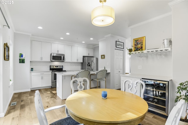 dining room featuring light wood-style flooring, recessed lighting, beverage cooler, and ornamental molding