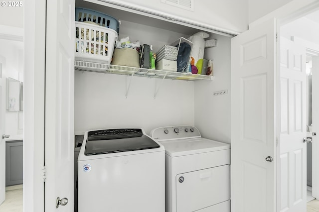 clothes washing area with visible vents, laundry area, and washing machine and clothes dryer