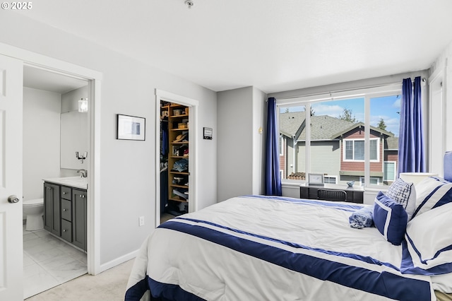 bedroom with baseboards, ensuite bath, a closet, a walk in closet, and marble finish floor