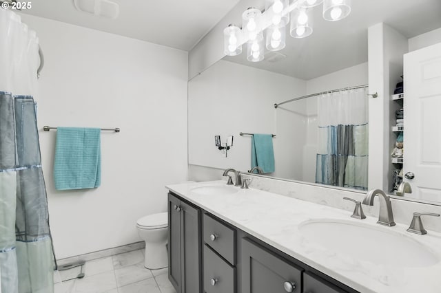 full bath featuring a sink, toilet, marble finish floor, and double vanity