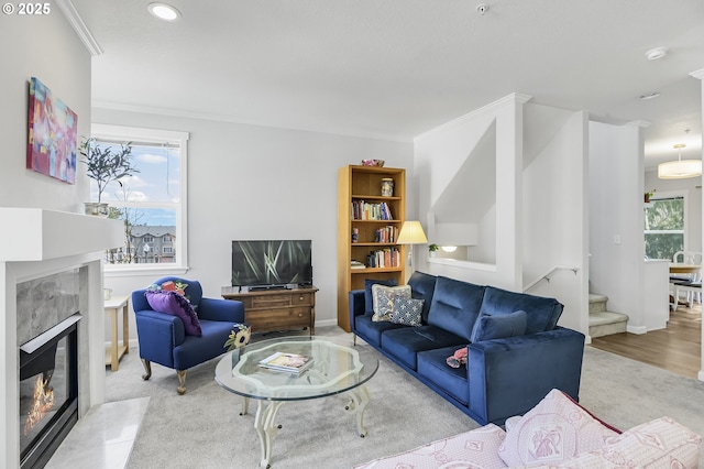 carpeted living area featuring stairs, recessed lighting, a healthy amount of sunlight, and a premium fireplace