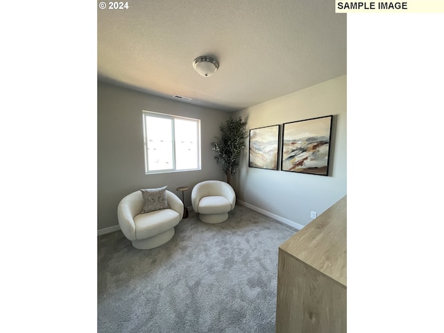 living area featuring a textured ceiling, carpet flooring, visible vents, and baseboards