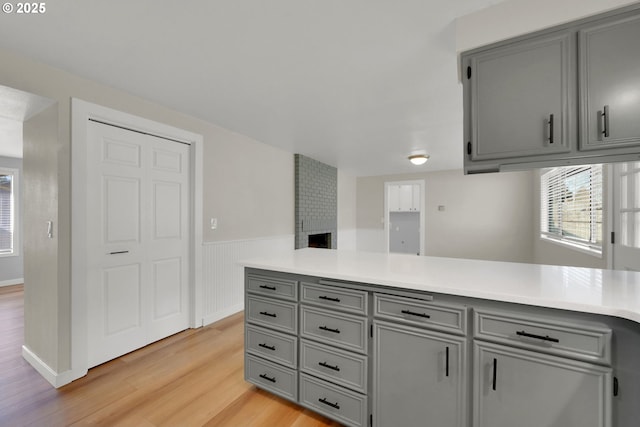 kitchen with light hardwood / wood-style flooring, a fireplace, gray cabinets, and kitchen peninsula