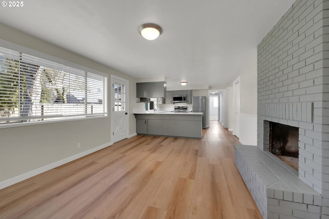 unfurnished living room featuring a brick fireplace and light wood-type flooring