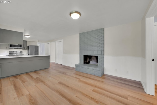 unfurnished living room featuring a fireplace and light hardwood / wood-style floors