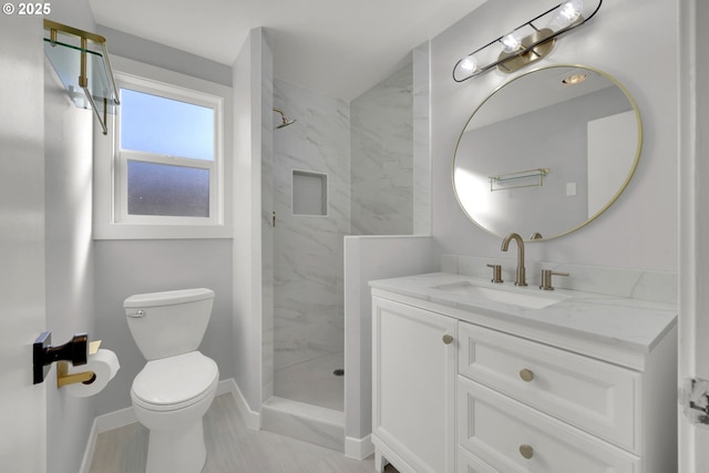 bathroom with a tile shower, vanity, and toilet