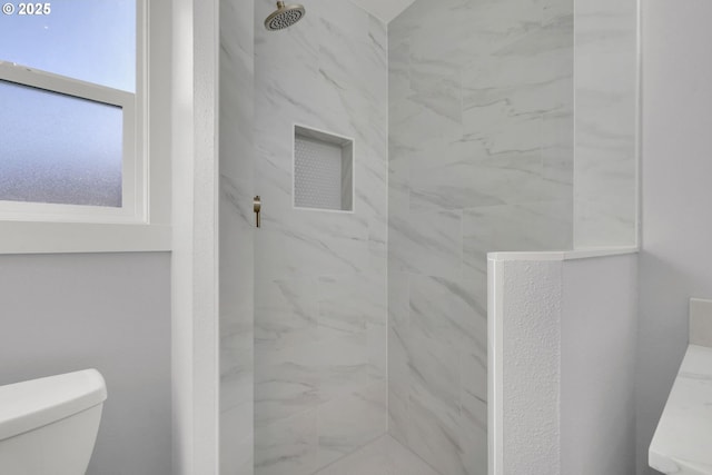 bathroom featuring tiled shower and toilet